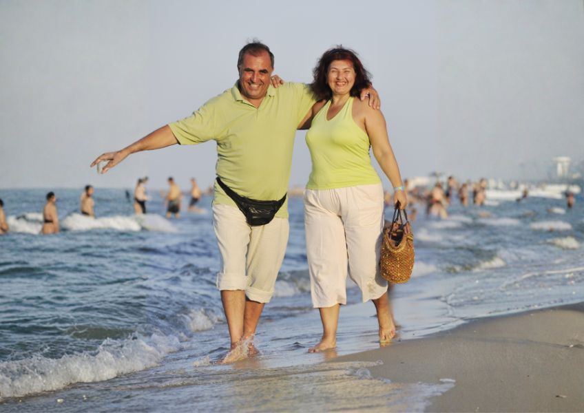 Casal caminha na praia e eles sabem que homens e mulheres emagrecem de forma diferente.