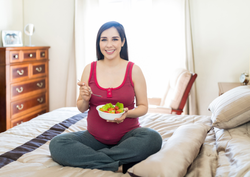 Gestante está comendo uma alimentação saudável no quarto.