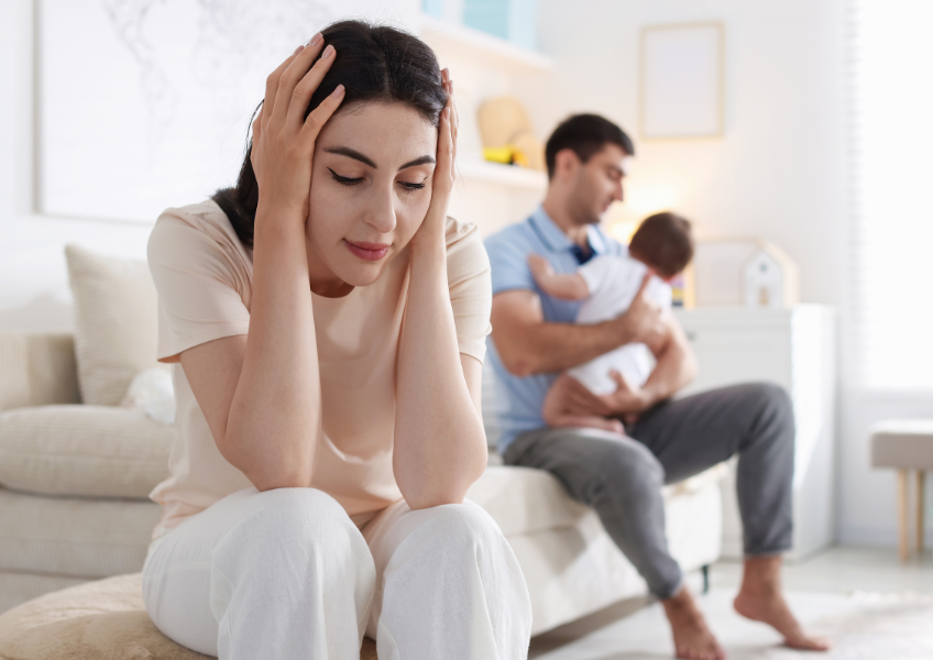 Mulher no puerpério está esgotada e sendo ajudada pelo marido.